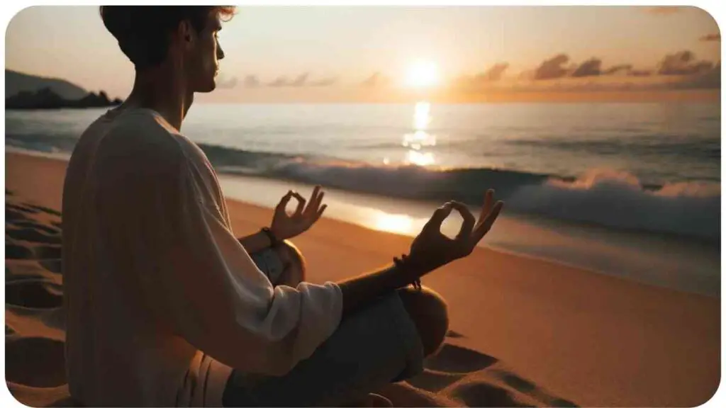 Photo of a calming beach scene during sunset. A person of European descent is seated on the sand, gazing at the horizon. Their hands are gracefully positioned in the Gyan Mudra, signifying the merging of individual soul with universal consciousness.