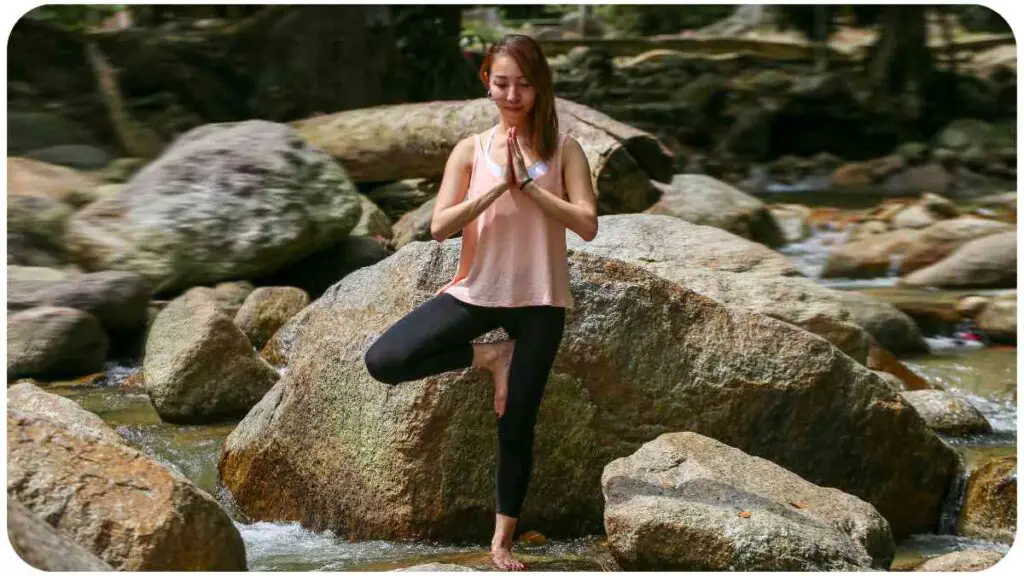 a person is doing yoga on a rock in the middle of a river.