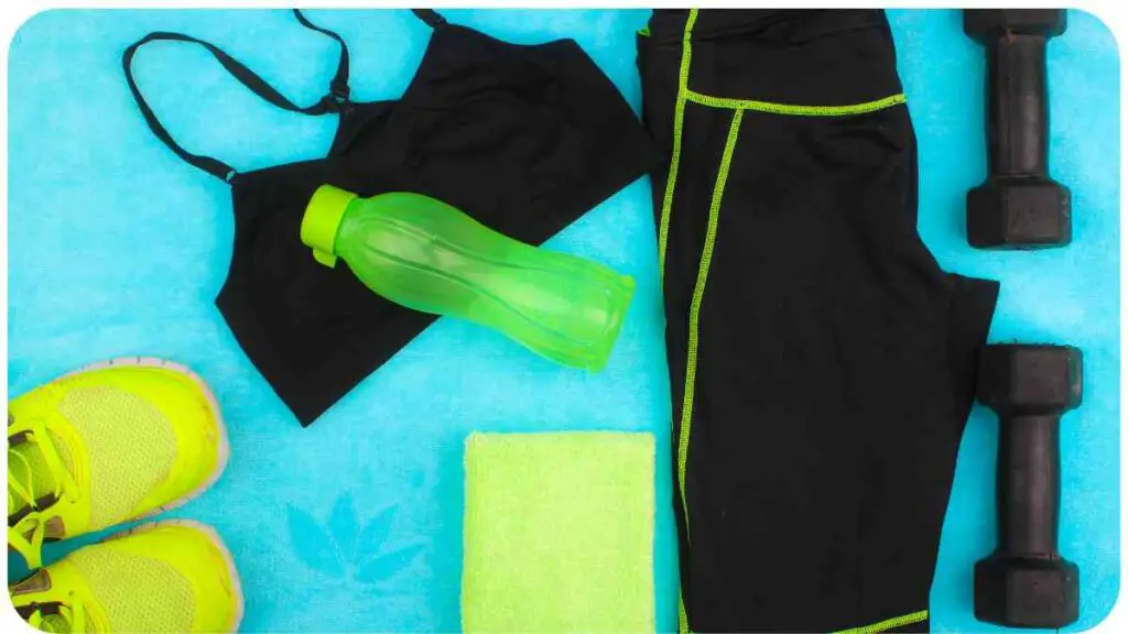 a pair of black sports clothes, a bottle of water, and a pair of dumbbells