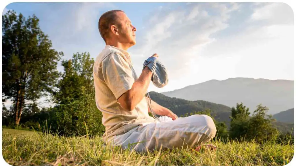 a person meditating in the grass with mountains in the background