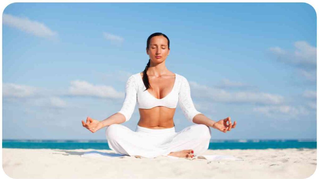 a person in white clothes meditating on the beach