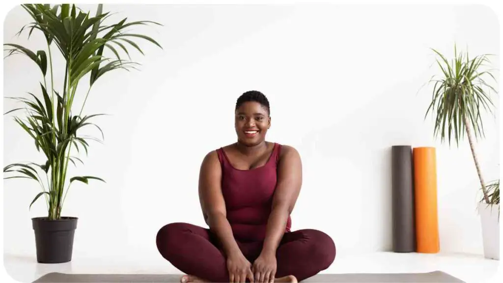 a person is sitting on a yoga mat in front of a potted plant