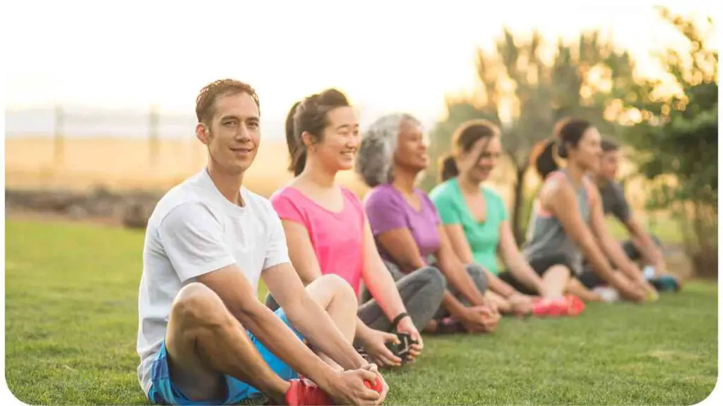 a group of people sitting on the grass in a yoga pose